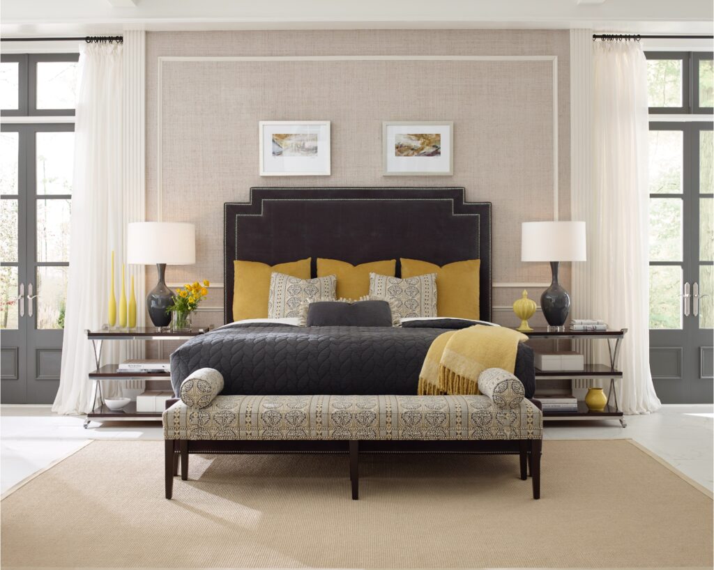 A bedroom with a bed and a bench with touches of yellow.